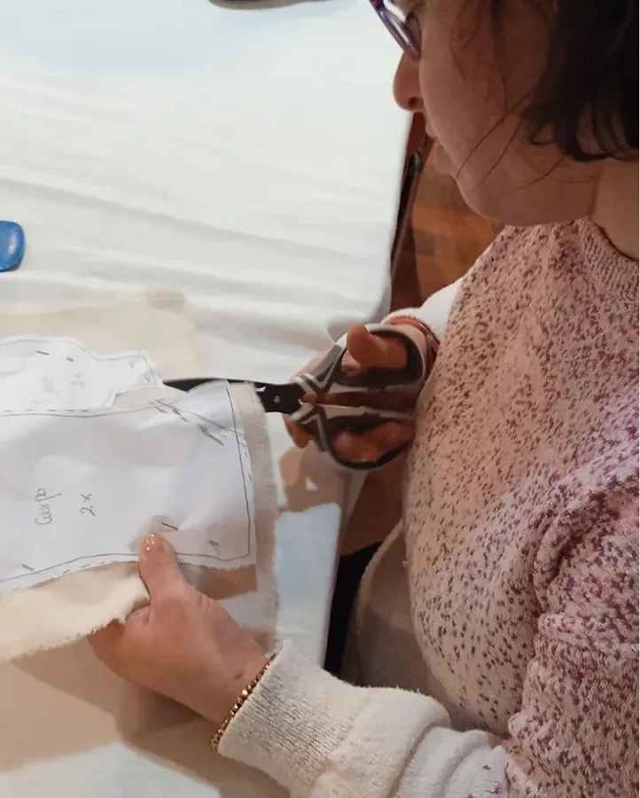 Chica de la Asociación Raitana cortando tela para coser una pieza de ropa